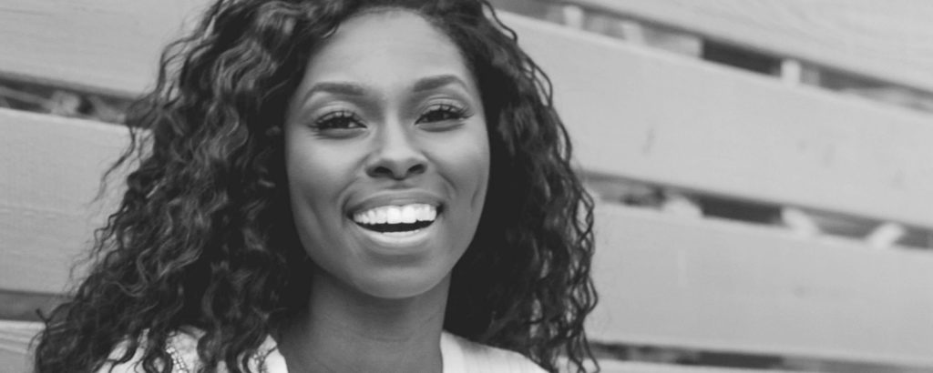 Smiling woman with long curly hair, showcasing bright, even teeth, representing cosmetic dentistry results