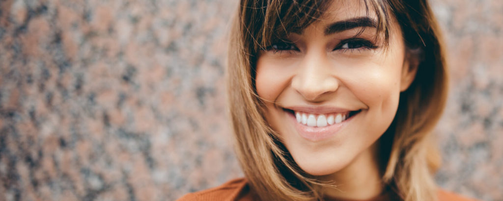 Smiling woman with straight, bright teeth, representing the results of a smile makeover