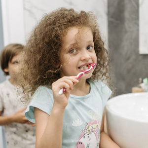 Pediatric dentist in Raleigh teaching a child to brush her teeth.