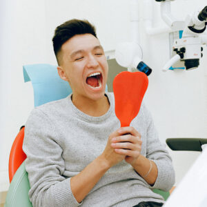 patient looking at his restored smile after getting oral surgery in Raleigh, NC